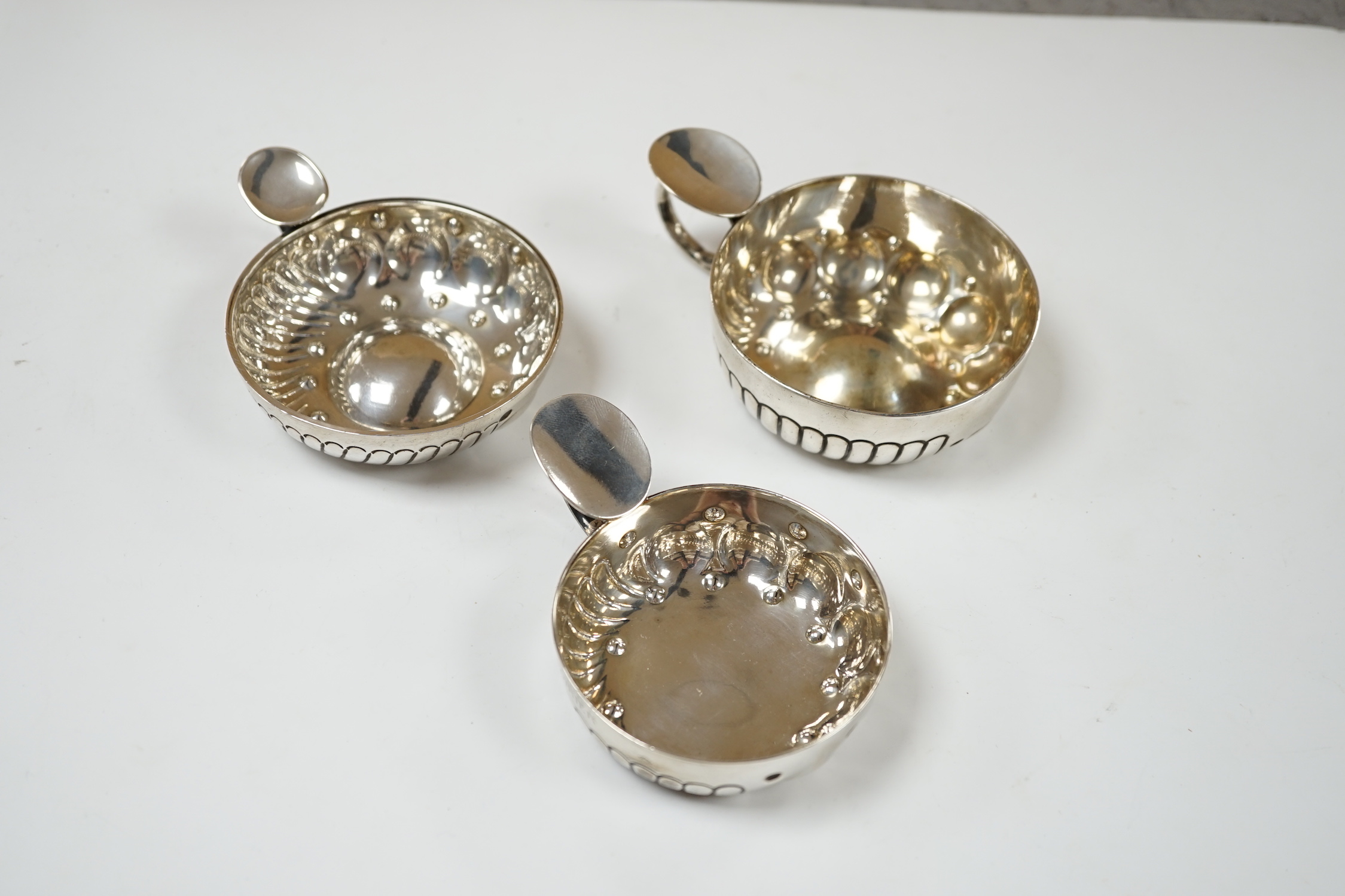 Three assorted late 19th/early 20th century French white metal taste vin, largest 11.1cm over handle.